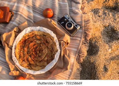 Upper view shot of the apple pie placed on the blanket with apples and vintage film camera