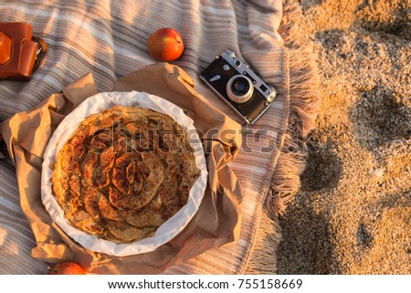 Upper view shot of the apple pie placed on the blanket with apples and vintage film camera
