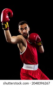 Uppercut position. Portrait of one professional boxer in red uniform training isolated over black background. Fighter practicing in action. Health, sport, motion concept. Copy space for ad.
