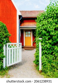 Uppsala Sweden June 17 2017. Traditional Swedish Red Colored Country House Outside Uppsala. Open Gate To A Garden In Sweden. Blue Sky In The Background. Red Wooden House In Swedish Rural Area.