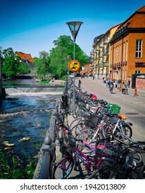 Uppsala Sweden May 17 2019. Bicycle Stand In The City Center Of Uppsala. Small Water Fall In The River. Old Buildings In Scandinavian Town. People Walking In Swedish City North Of Stockholm.