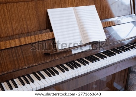 Upright piano with empty music notation book and labeled keyboard. Music education setup for beginner piano lessons and learning exercises