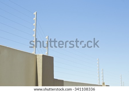 upright poles holding electric fencing cable on a boundary wall