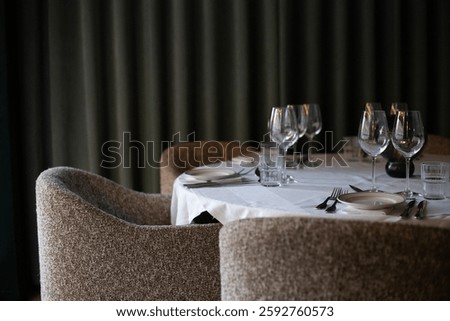 An upscale dining table arranged for a formal dinner, featuring fine glassware, neatly folded napkins, and a soft, ambient glow. The setting exudes elegance, a sophisticated restaurant