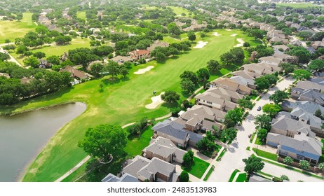 Upscale golf community in master planned subdivision urban sprawl, grassy fairway, sand trap bunkers, golfer playing with expensive new development two story mansion houses, Plano Texas, aerial. USA