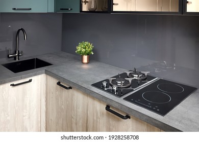Upscale modern flat design Aqua Menthe kitchen in luxury home with induction electric hob flat oak or walnut wooden panels with flower in vase and sink with tap mixer of modern design.