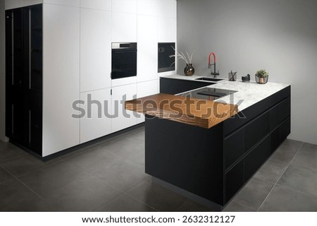 Upscale modern flat design loft kitchen with Induction cooker black glass hob with integrated hood or aspirating induction hob on marble light stoneware countertop, vase, sink and large cutting board.