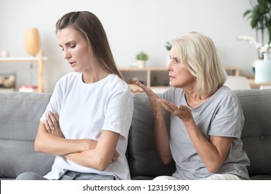 Upset adult daughter ignoring not listening to senior old strict mother in law arguing moralizing scolding controlling showing authority to stubborn young woman, different generation conflict concept
