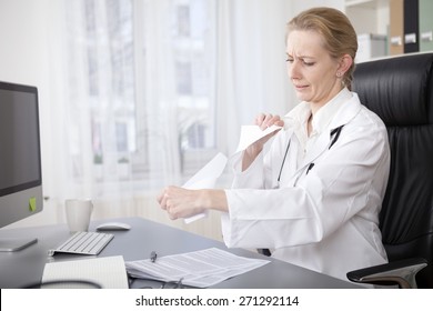 Upset Adult Female Doctor Shredding Some Medical Papers While Sitting At Her Office.