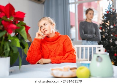 Upset adult woman ignoring her daughter, standing behind her, during Christmas weekend - Powered by Shutterstock