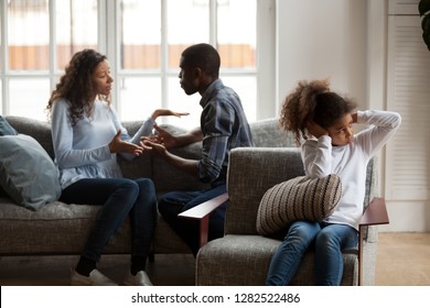 Upset African American Kid Daughter Closing Ears Not Listening To Noisy Shouting Parents Fighting Arguing At Home, Sad Preschool Mixed Race Child Girl Stressed With Mom And Dad Black Family Conflict