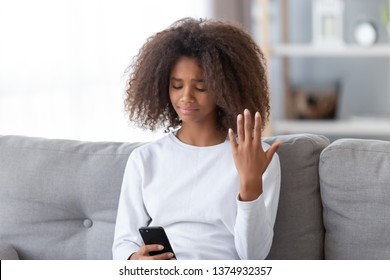 Upset African American Teen Girl Using Phone, Received Unpleasant Message, Sitting On Couch, Feeling Unhappy, Teenage Problem Concept, First Love And Jealousy, Broken Friendship, Bad News