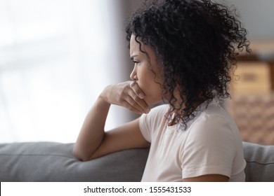 Upset African American woman thinking about bad relationships problems, break up with boyfriend close up, worried girl sitting on sofa alone at home, suffering from loneliness, feeling sad - Powered by Shutterstock