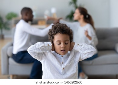 Upset african kid son closing ears not listening parents fighting arguing at home, unhappy sad stressed little mixed race hurt by divorcing mom and dad conflicts, children and family problems concept