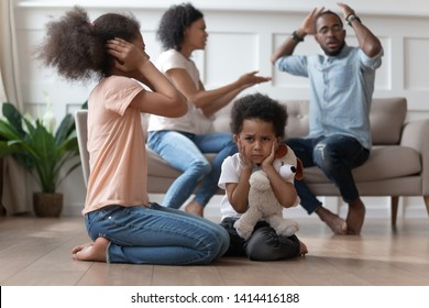 Upset african kids closing ears hurt by parents fighting arguing at home, sad stressed little innocent children suffer from family problems conflicts, unhappy mom dad shouting quarreling divorcing