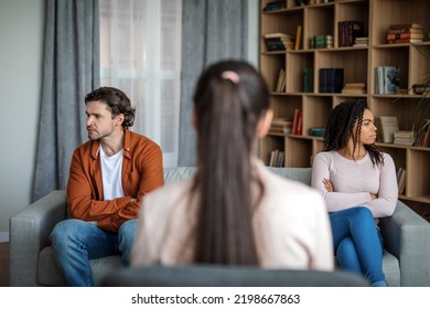 Upset Angry Young Black Wife Ignores Caucasian Husband At Meeting With Doctor Psychologist In Office Clinic Interior. Family Psychological Therapy, Treatment Of Mental Problems, Conflict And Quarrel