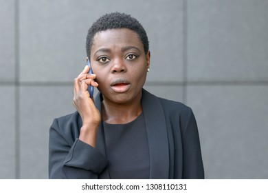Upset anxious young woman talking on a mobile phone looking at camera with a sympathetic expression as she listens to the call - Shutterstock ID 1308110131