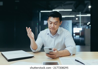 Upset Asian Businessman Working In Office, Reading Bad News On Phone, Man Depressed At Work