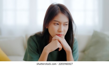 Upset asian woman frustrated by problem with work or relationships, sitting on couch, feeling despair and anxiety, loneliness, having psychological trouble - Shutterstock ID 2201960327