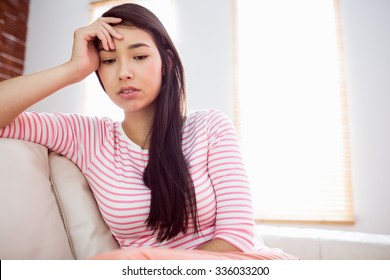 Upset Asian Woman On Couch At Home In The Living Room