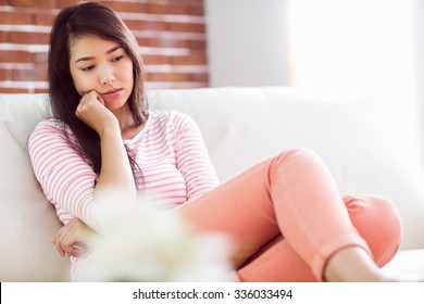 Upset Asian Woman On Couch At Home In The Living Room