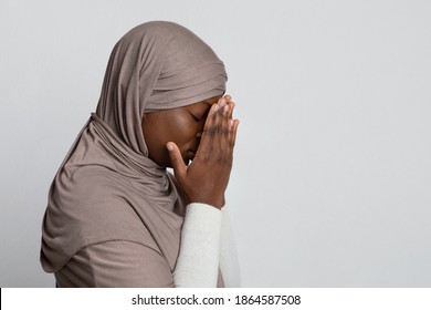 Upset Black Islamic Lady In Hijab Covering Face With Hands, Depressed African Muslim Woman In Headscarf Standing Over Light Background, Feeling Ashamed, Profile Portrait With Copy Space