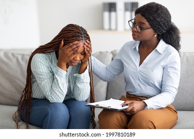 Upset black lady with nervous breakdown consulting psychologist, having session with counselor at clinic. Professional psychotherapist comforting depressed female patient at office - Shutterstock ID 1997810189