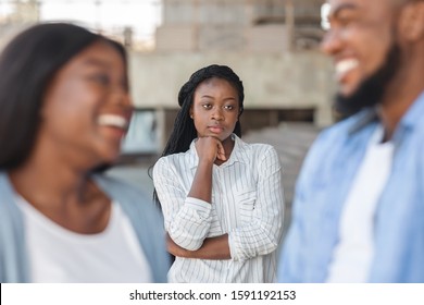 Upset black woman watching her ex boyfriend happy in relations with new girlfriend, looking jealous on background, selective focus