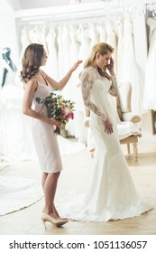 Upset Bride With Friend Holding Flowers In Wedding Salon