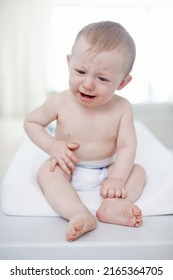 Upset By A Tummy Ache. A Crying Baby Boy Sitting On A Changing Table.