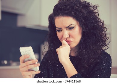 Upset confused young woman suing mobile phone reading text message 