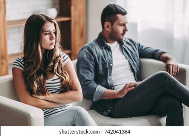 Upset couple at home. Handsome man and beautiful young woman are having quarrel. Sitting on sofa together. Family problems. - Shutterstock ID 742041364