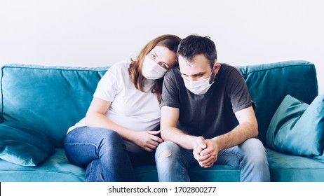 Upset Depressed Melancholy Sad Quarantined Coronavirus Family In Medical Masks. People In Anxiety And Fear Because Of Corona Virus. Stay Home Self-isolation. Pregnant Woman And Man Millennials.