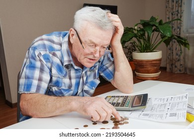Upset depressed Senior man sitting at the table and calculating finances. Old man checking bills. Man counting coins on the table. Pension calculation concept                                  