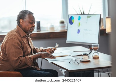 Upset depressed Senior man sitting at the table and calculating finances. Old man checking bills. Man counting coins on the table. Pension calculation concept