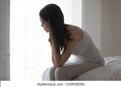 Upset depressed young woman sitting on bed, looking to aside, thinking about problems, making decision, unhappy sad girl lost in thoughts, suffering from divorce or break up in relationship - Shutterstock ID 1769928356