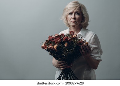 Upset Elderly Woman Hold Withered Dry Old Rose Flowers Bouquet. Old Age Concept Symbol.
