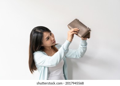 Upset Female With Empty Wallet. Poor Young Asian Woman Shows Her Empty Purse. Bankruptcy, Financial Crisis Concept. Studio Shot Isolated On White Wall. Copy Space