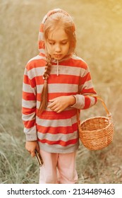 Upset Or Focused Eight Year Old Kid Girl Mushroom Picker Is Seek For And Picking Mushrooms In The Forest. Child Survivalists Gathers A Wild Fungus Harvest And Outdoor Foraging  In Nature. Flare