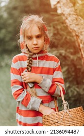 Upset Or Focused Eight Year Old Kid Girl Mushroom Picker Is Seek For And Picking Mushrooms In The Forest. Child Survivalists Gathers A Wild Fungus Harvest And Outdoor Foraging  In Nature. Flare