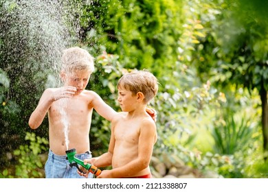 Upset and frightened boy does not want to play with his little brother with water hose in backyard outdoor in sumer time. Panicking funny blond brother afraid of cold water. - Shutterstock ID 2121338807