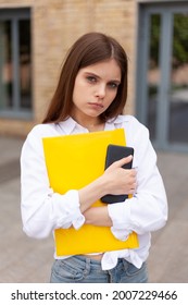 Upset Girl Student With A Folder Outdoors. Bullying At The University. Public Humiliation.