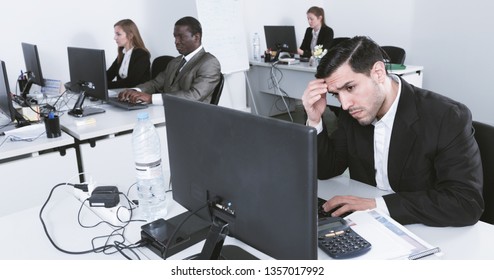 Upset Hispanic diligent serious efficient businessman worriedly looking at computer monitor in modern open plan office