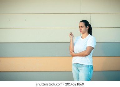 An Upset Hispanic Female  Standing Next To A Wall