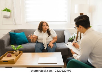 Upset hispanic woman with anger issues talking and screaming to her therapist while coming to anger management