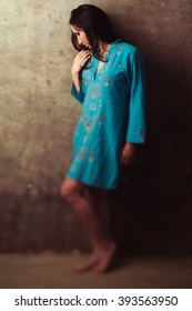 Upset Indian Girl In Blue Dress Standing Against Stone Background. Offened Upset Indian Girl Against Wall.  Dissapointed East Girl In Blue Dress. 