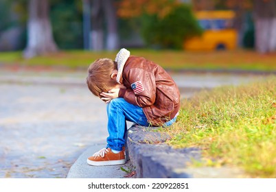 Upset Kid Boy Sitting Alone In City Park