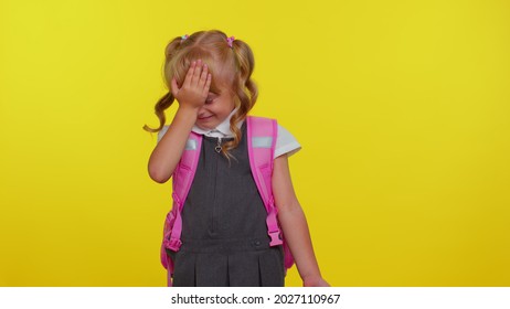 Upset Little Blonde Teen Child Kid Girl In School Uniform Making Face Palm Gesture, Feeling Bored, Disappointed In Result, Bad News On Yellow Studio Background. Back To School. Childhood Lifestyle