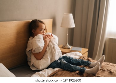 Upset Little Girl Crying Sitting Alone In Fetal Position Hiding Face And Rocking On Bed Hugging Big Pillow. Concept Of Child Depression.