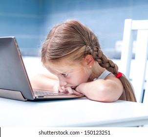 Upset Little Girl With Her Computer At Home At The Table